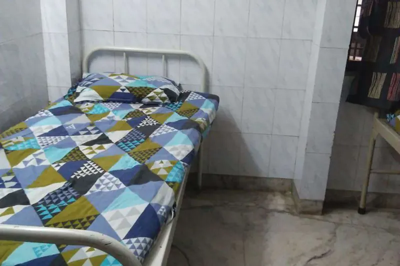 A single bed in a small tiled ward of the old hospital