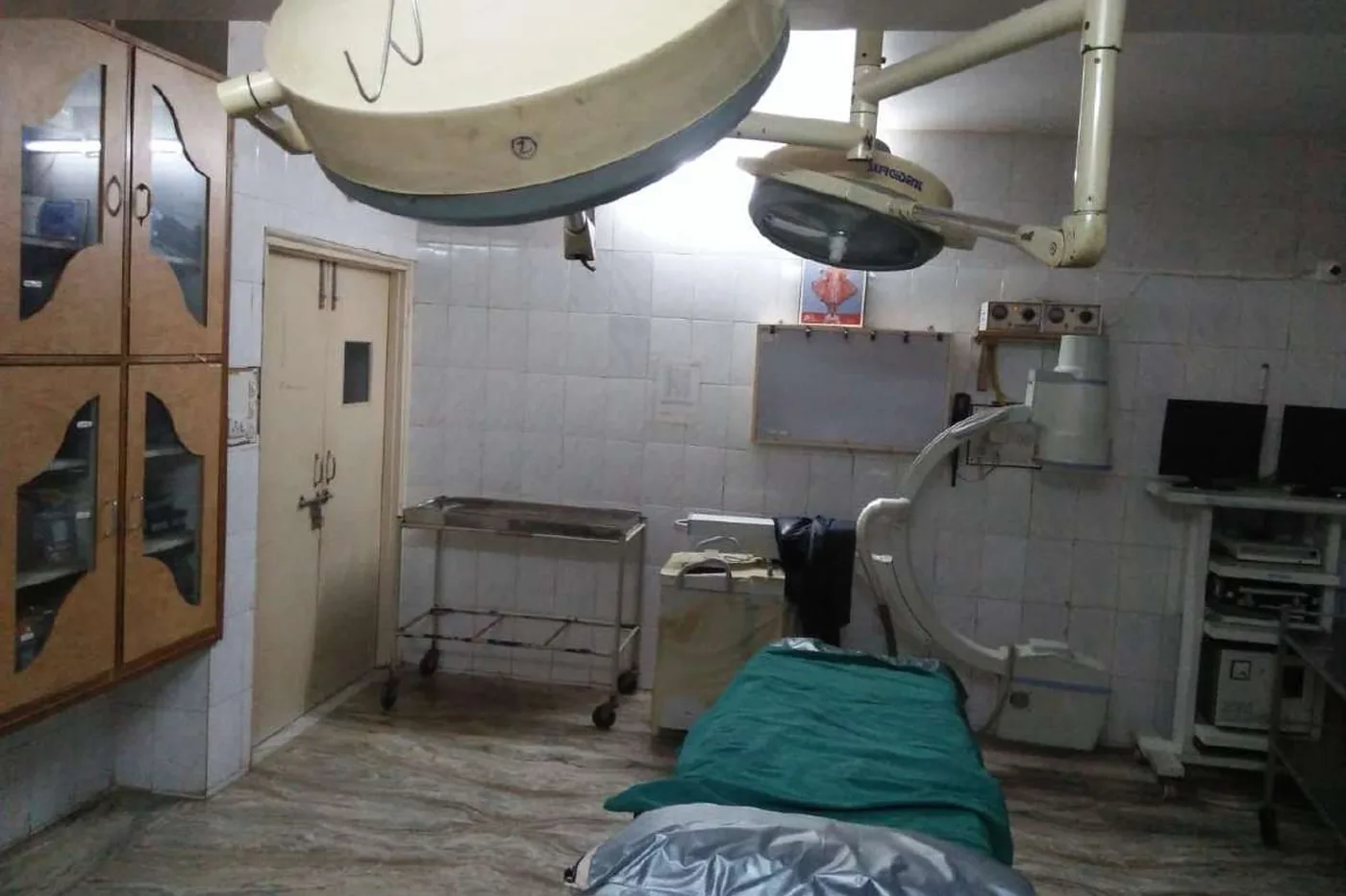 The same operating theatre before the rebuild, with tiled walls and an image intensifier beside the table