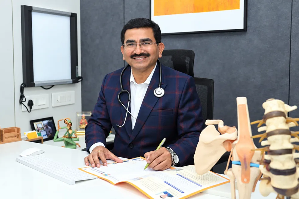 Dr. Arvind Shiroya at his desk with spine and knee models